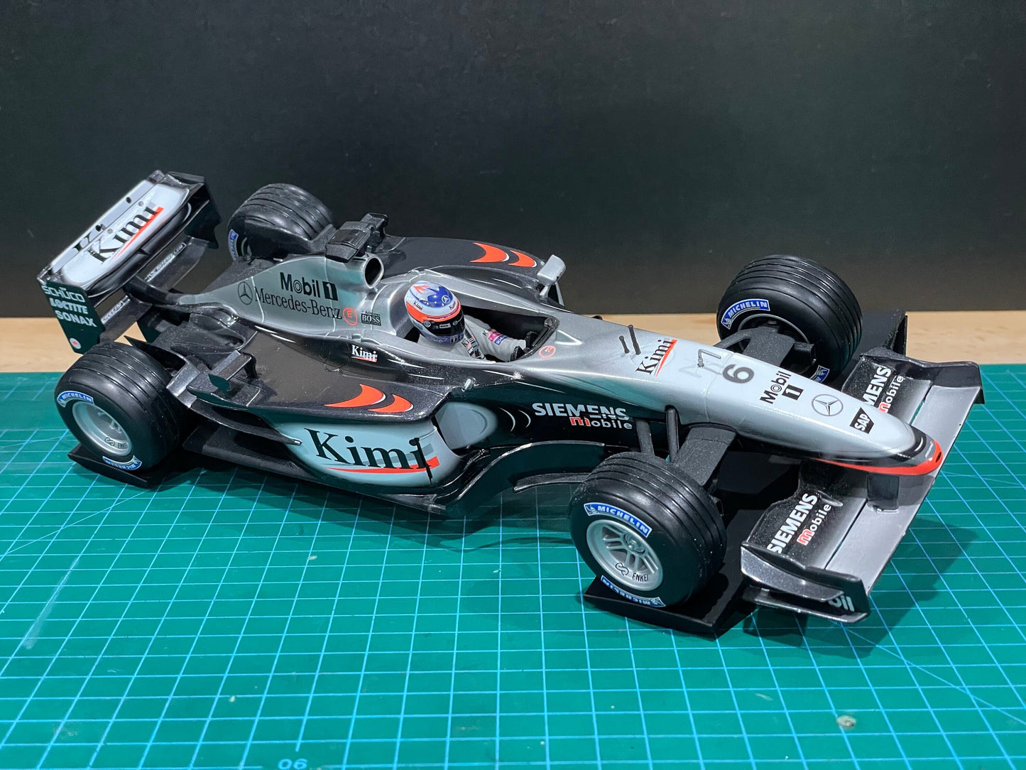 1:18 scale diecast model of the McLaren Mercedes MP4-17D Formula 1 car with Kimi Räikkönen livery, displayed on a cutting mat for detailing or setup.