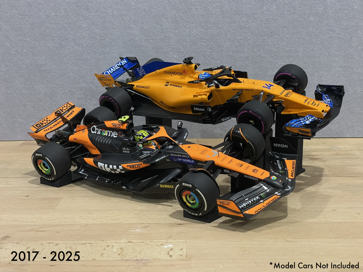 Two 1:18 model Formula 1 cars on stands against a gray background