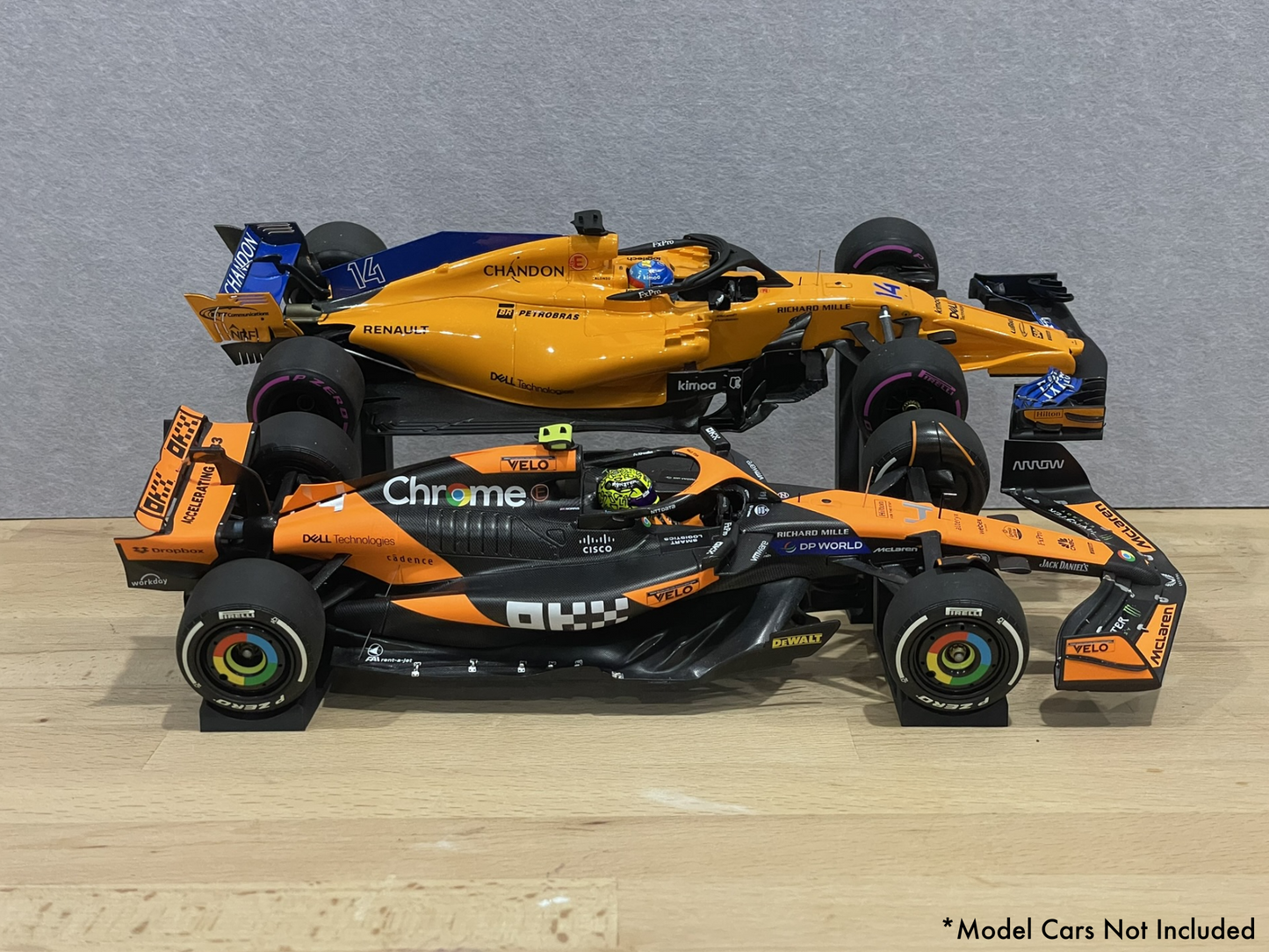 Two 1:18 model McLaren Formula 1 cars on stands against a gray background